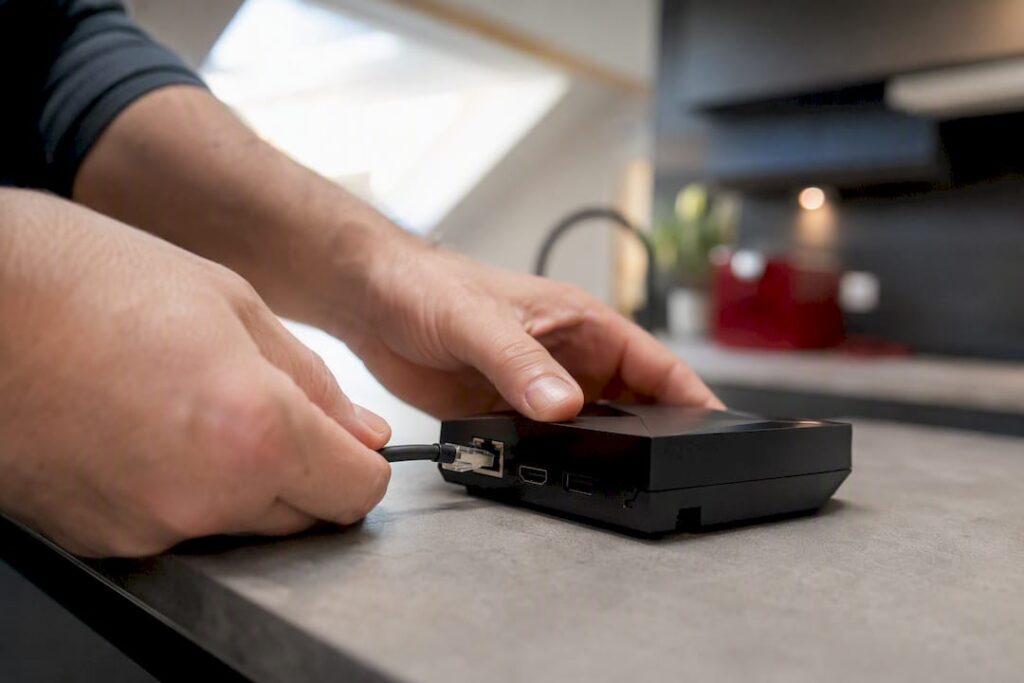 Hands connecting Ethernet cable to streaming box
